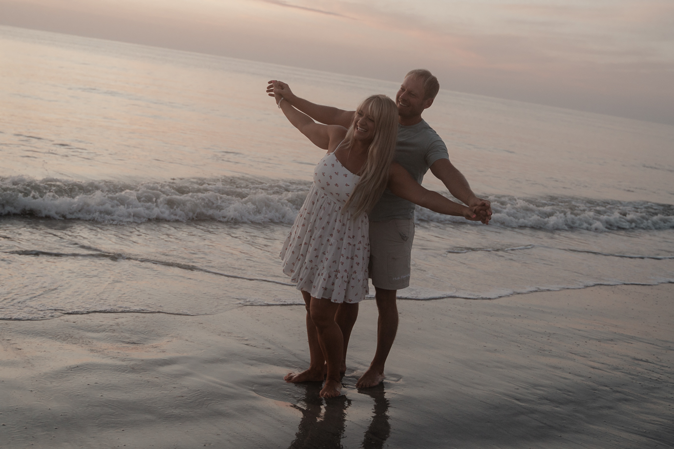 Couple dancing and laughing in the surf during Florida sunrise couples session