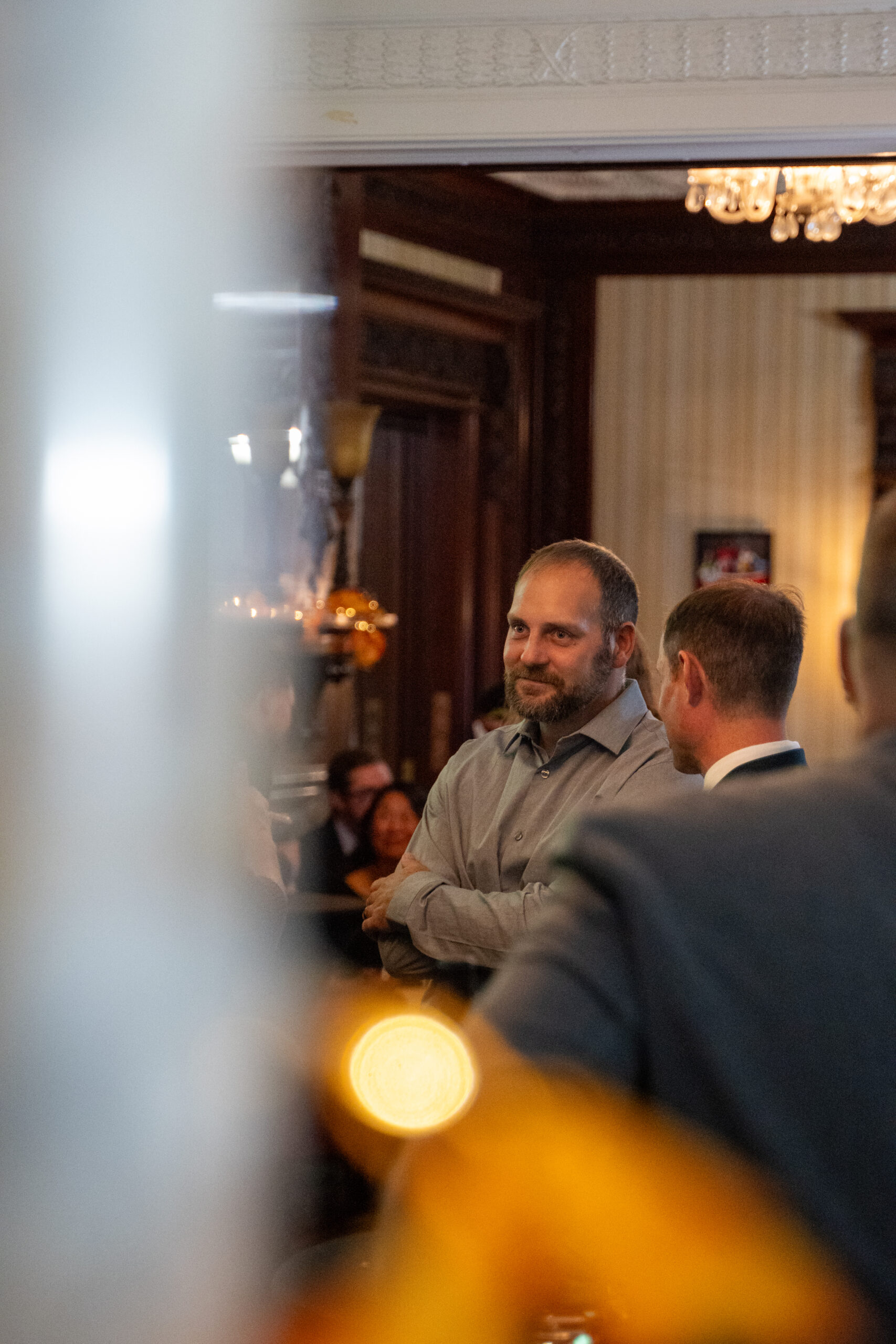 Guests chatting beneath ornate wall sconce at the mansion