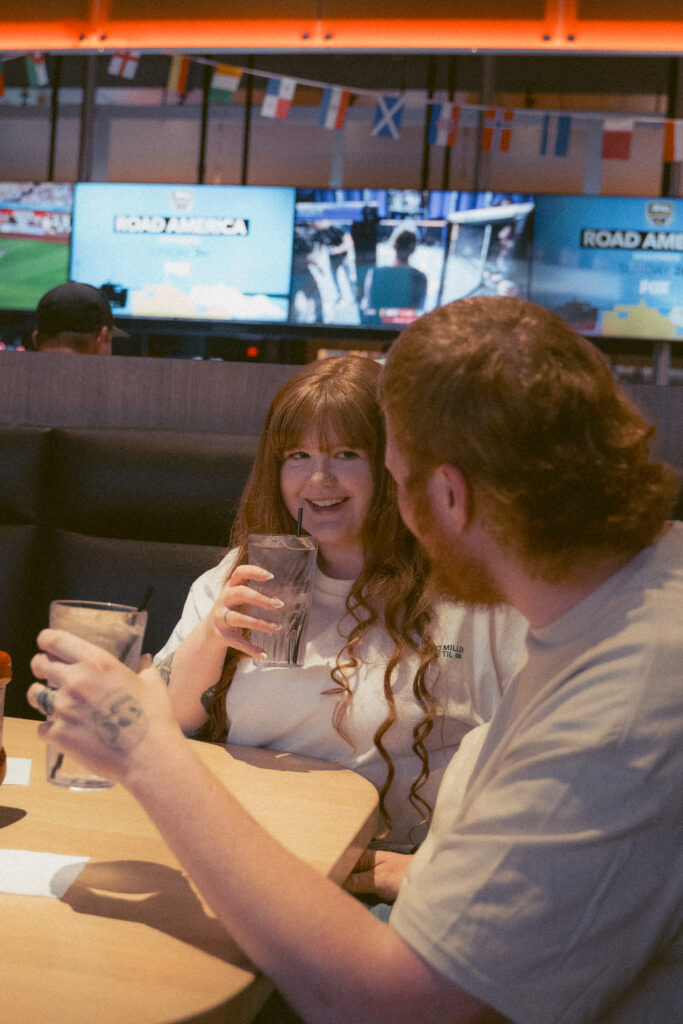 Playful diner engagement photo of a couple sharing dessert together