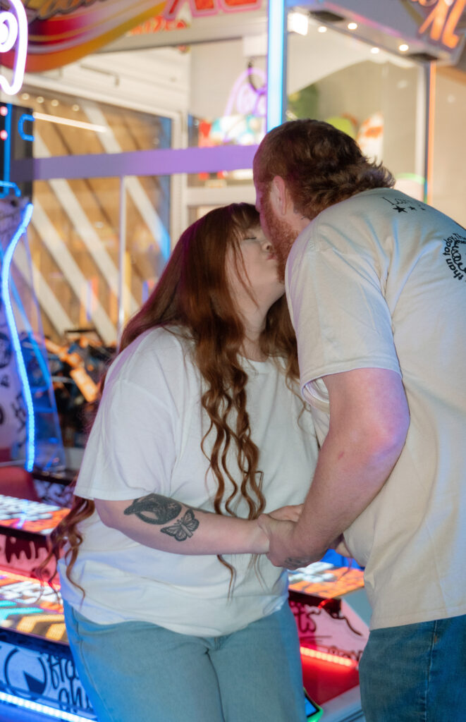 Couple playing arcade games during a fun engagement session in Davenport Iowa