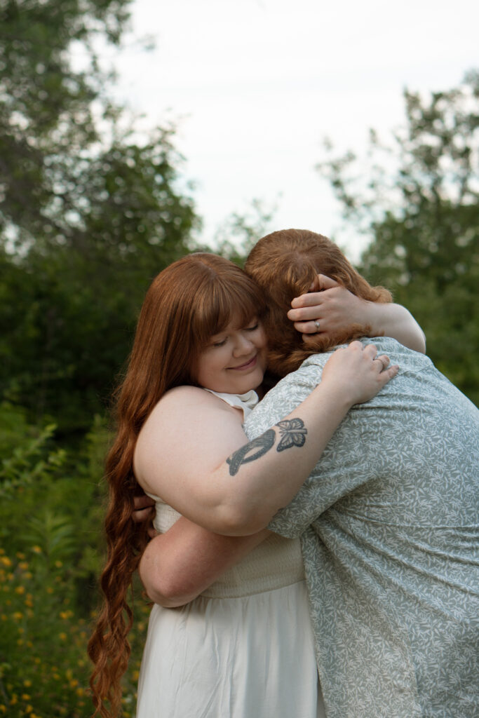 Couple holding each other in a flower field during outdoor engagement photos