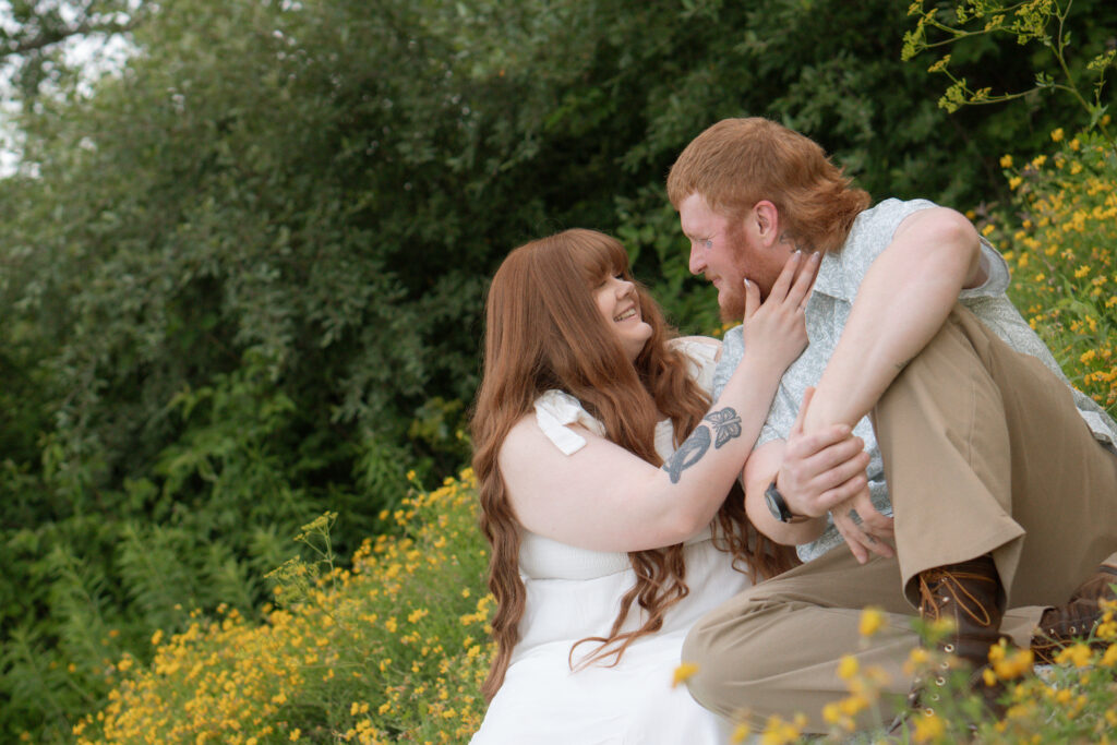 Couple cuddling in a yellow flower field during a Davenport Iowa engagement session