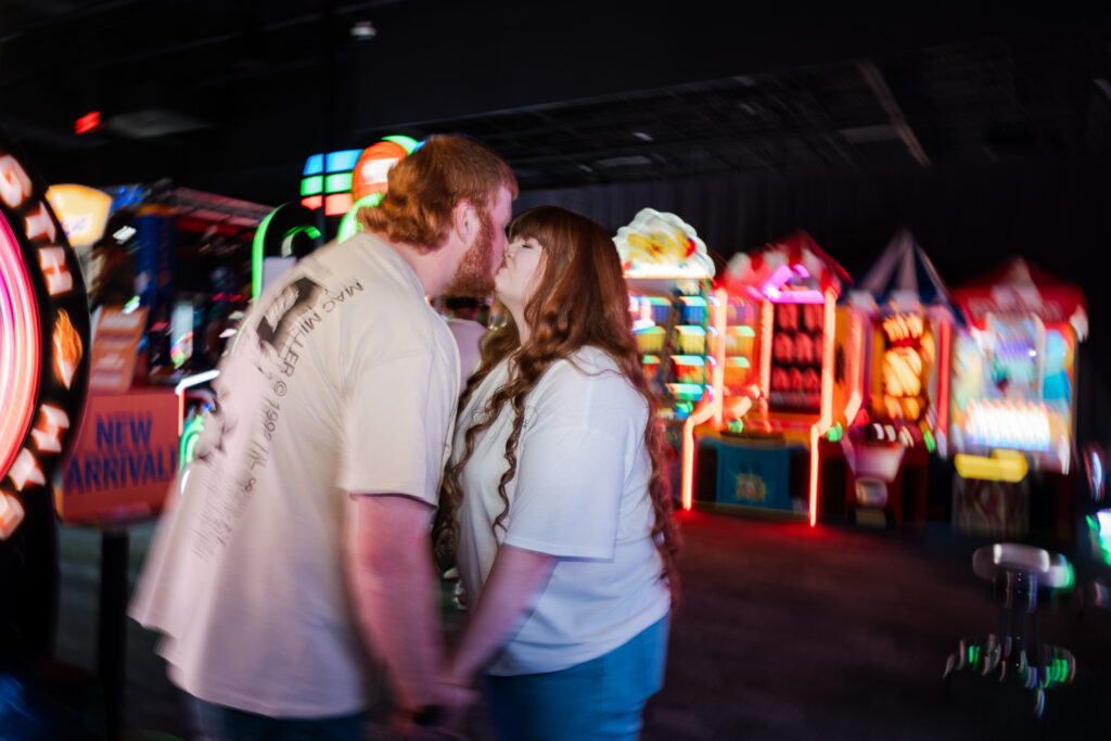 Couple playing arcade games during a fun engagement session in Davenport Iowa