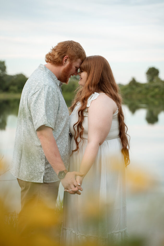 Engaged couple holding hands by the water during Davenport Iowa engagement photos